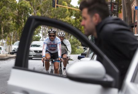 Person getting out of car in front of cyclist 