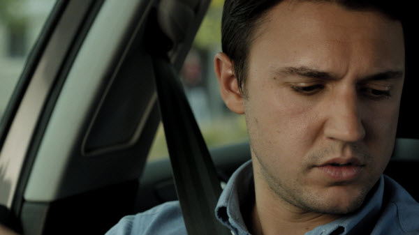 Man looks down at his phone while driving