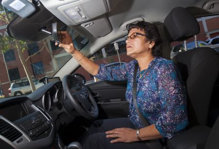 Older driver inspecting rearview mirror