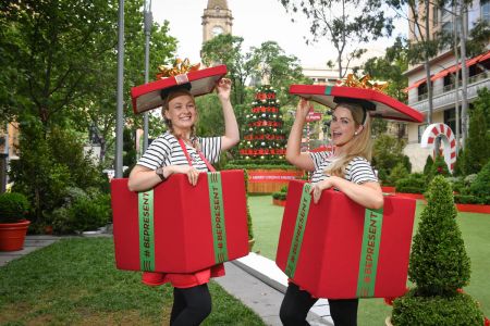 People dressed as presents in front of big christmas tree
